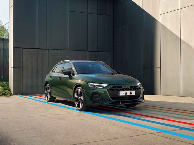 Dunkelgrüner Audi A3 Sportback steht vor einem grauen Gebäude.