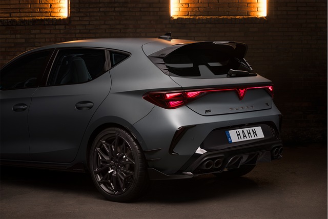 Heckansicht eines mattschwarzen CUPRA Leon VZ mit ABT-Kooperation, erkennbar am markanten Heckspoiler, den sportlichen Felgen und dem beleuchteten CUPRA-Logo vor einer Ziegelsteinwand.