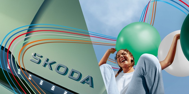 Nahaufnahme eines Skoda-Logos mit einer Frau, die einen grünen Ballon hält.