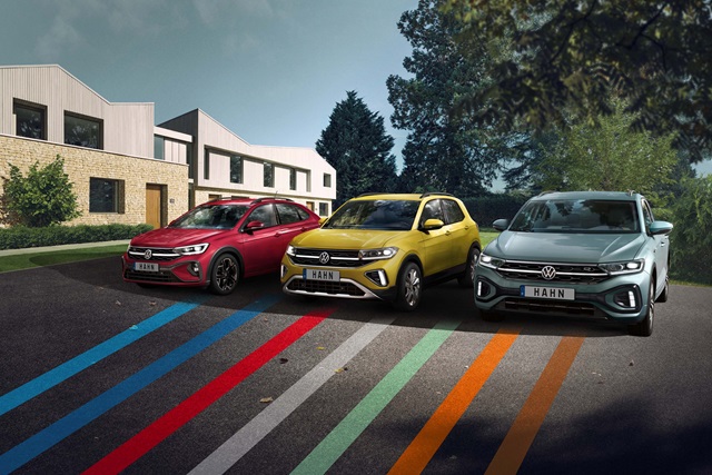 Drei verschiedene, bunte Volkswagen-Modelle nebeneinander parkend in einer modernen Umgebung.