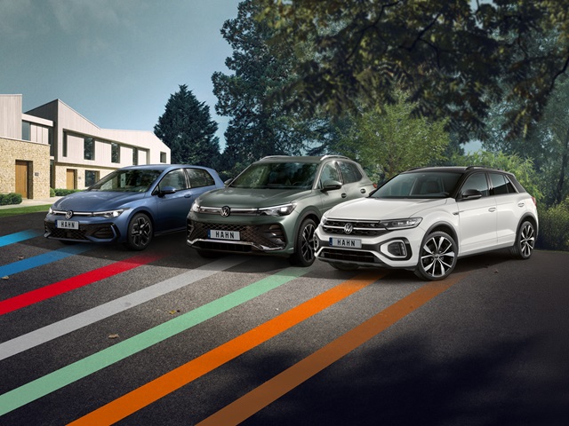 VW Golf, Tiguan und T-Roc nebeneinander geparkt vor modernen Wohnhäusern und Bäumen