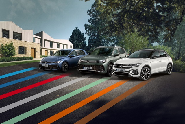 VW Golf, Tiguan und T-Roc nebeneinander geparkt vor modernen Wohnhäusern und Bäumen