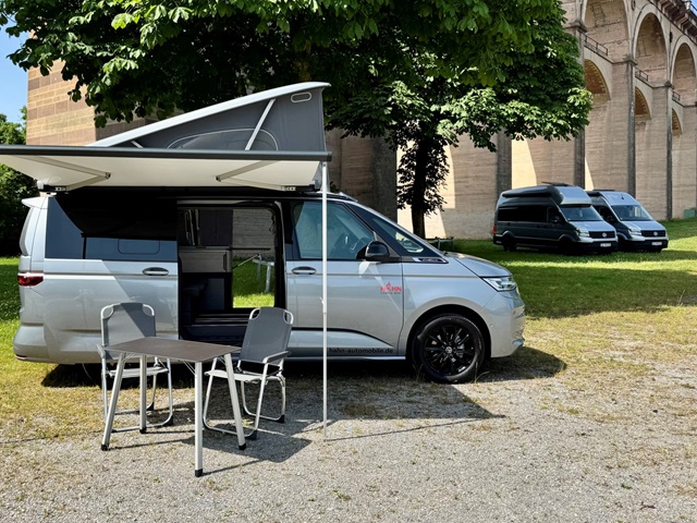 Ein VW California Camper mit einem Tisch und Stühlen vor dem Bietigheimer Viadukt.