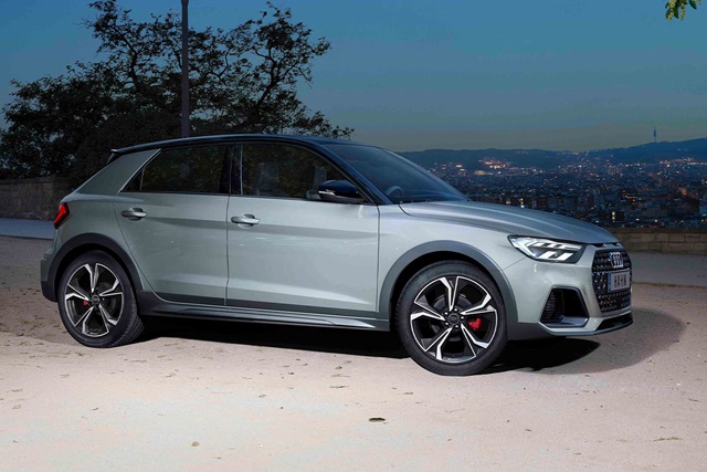 Seitenansicht eines grauen Audi A1 Allstreet mit schwarzen Akzenten und markanten Felgen vor einer nächtlichen Stadtlandschaft
