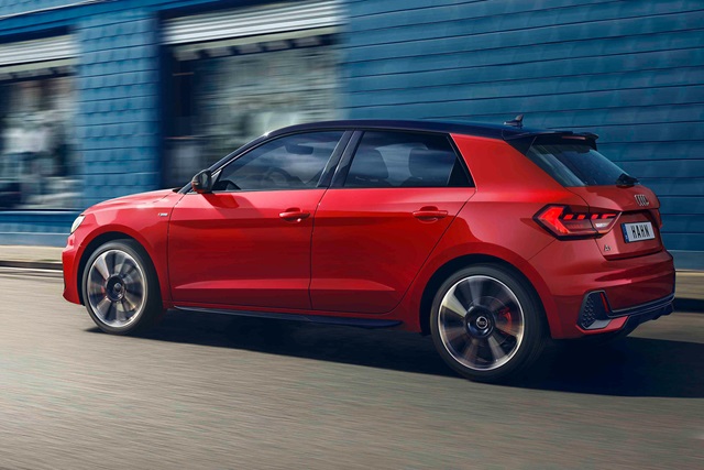 Roter Audi A1 Sportback in Seitenansicht auf Straße mit moderner Architektur im Hintergrund