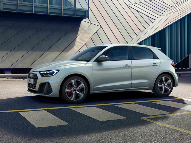 Silberner Audi A1 Sportback in Seitenansicht vor moderner Architektur mit geometrischen Fassadenelementen