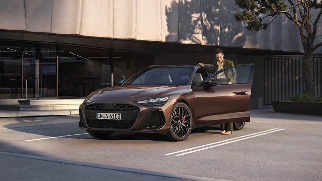 Der Audi A6 Avant parkend vor einem modernen Gebäude mit einer Person, die auf der Fahrerseite einsteigt. 