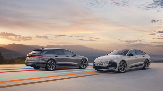 Zwei Audi A6 e-tron in Seitenansicht auf einer Straße mit farbigen Linien vor einem Bergpanorama bei Sonnenuntergang