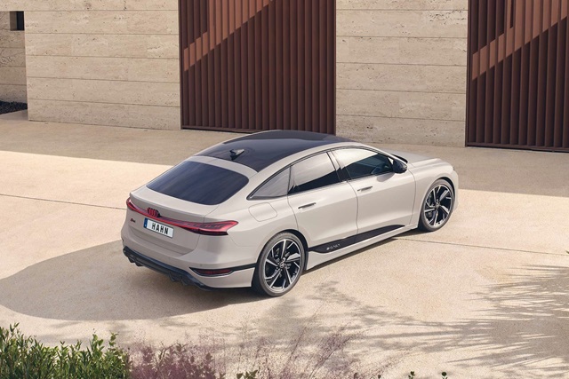Beige Audi A6 e-tron Sportback von hinten rechts mit schwarzem Dach vor moderner Fassade