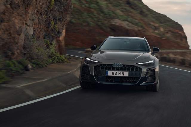 Audi A6 Allroad in Braun fährt auf kurviger Küstenstraße mit Felswand im Hintergrund
