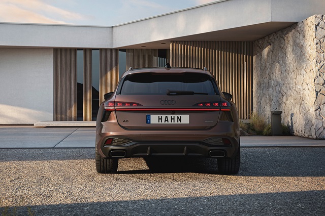 Heckansicht eines braunen Audi A6 Avant vor modernem Gebäude mit Holz- und Steinverkleidung