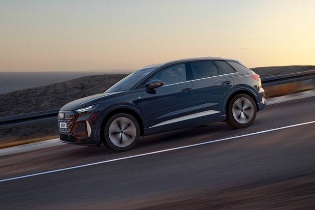Audi Q4 e-tron SUV in Seitenansicht auf einer Straße mit Geländehintergrund