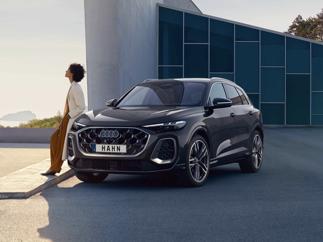 Eine Person lehnt lässig an einem Audi Q5 der in urbanen Umgebung parkt.