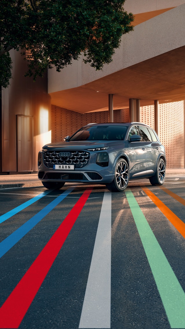 Audi Q7 SUV in Frontansicht vor modernem Gebäude mit farbigen Linien auf dem Boden