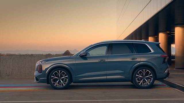 Seitenansicht eines blauen Audi Q7 SUV auf einem Parkplatz mit Brückenpfeilern im Hintergrund