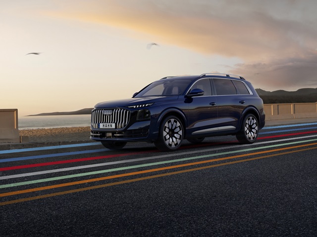 Seitenansicht eines blauen Audi Q9 SUV auf einer Straße mit farbigen Linien und einem Himmel bei Sonnenuntergang