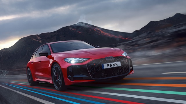 Roter Audi RS 5 Avant mit schwarzem Kühlergrill und LED-Scheinwerfern fährt auf einer Straße vor einem Vulkan mit Lavafluss