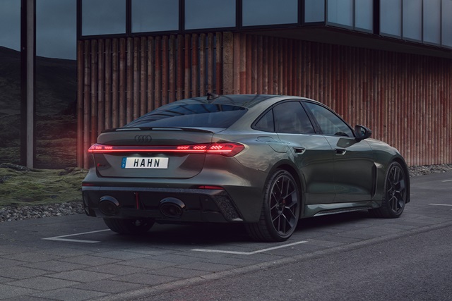 Audi RS 5 Limousine in Grün aus seitlicher Heckansicht mit schwarzer Felge und Heckleuchten, geparkt vor einer Fassade mit vertikalen Holzlatten
