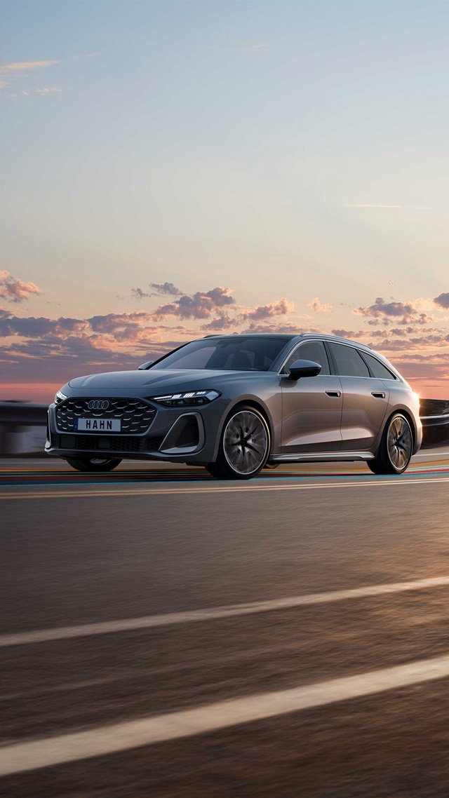Seitenansicht eines grauen Audi S5 Avant mit markantem Kühlergrill und sportlichen Felgen vor einem Himmel mit Wolken bei Sonnenuntergang
