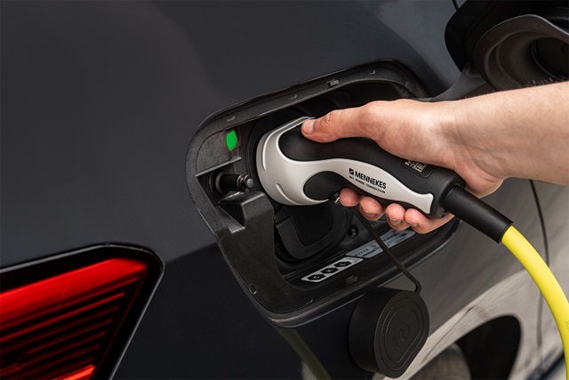 Hand steckt gelbes Ladekabel in Ladeanschluss eines CUPRA Born VZ.
