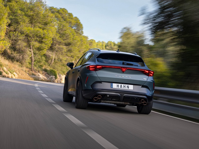 Heckansicht eines blauen Cupra Formentor VZ5 auf einer kurvigen Straße mit Wald im Hintergrund