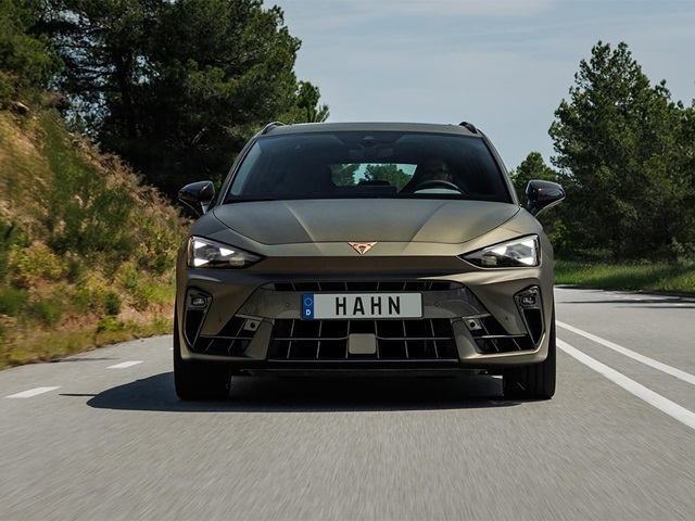 Frontansicht des braunen CUPRA Leon Sportstourer VZ Extreme mit markantem Kühlergrill und LED-Scheinwerfern auf einer Landstraße