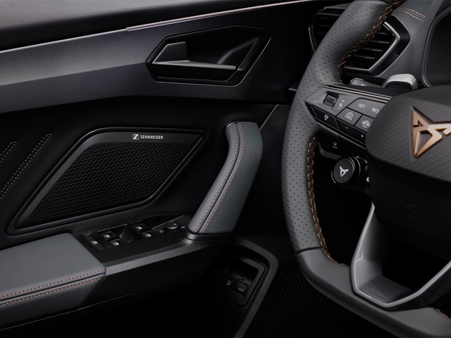 Nahaufnahme des Lenkrads mit Cupra-Logo und des Türinnenbereichs mit Sennheiser-Lautsprecher im Cupra Leon Innenraum