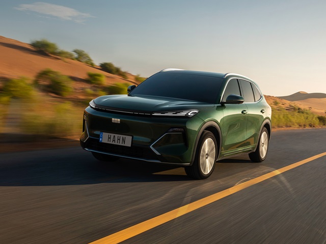 Grüner Geely Starray EM-i fährt auf einer Straße durch eine Wüstenlandschaft mit Hügeln im Hintergrund