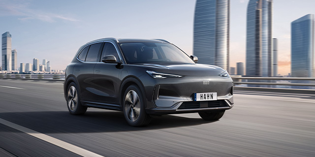 Geely E5 in Seitenansicht vor moderner Stadtlandschaft mit Hochhäusern bei Tageslicht