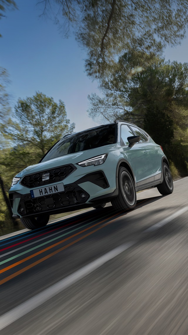 SEAT Arona SUV in Grau fährt auf einer Straße mit Bäumen im Hintergrund