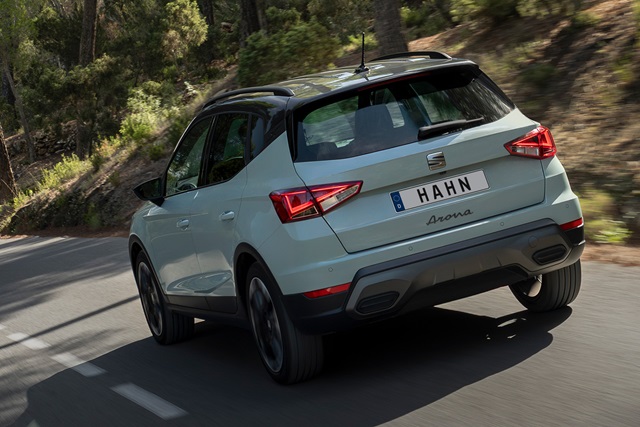 Heckansicht eines grauen SEAT Arona SUV auf einer kurvigen Straße mit Wald im Hintergrund