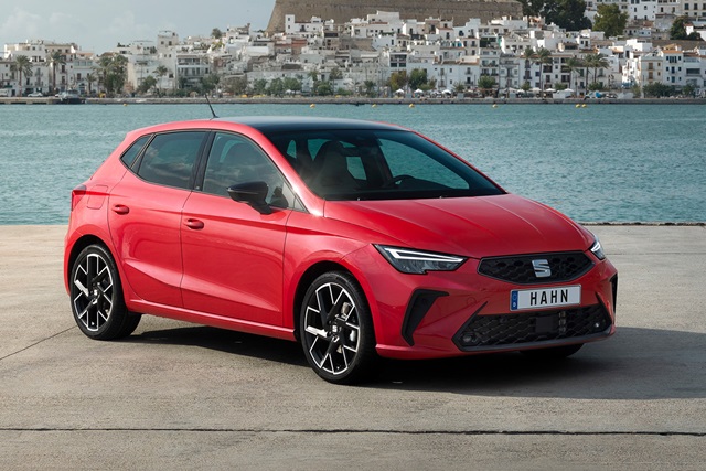Roter SEAT Ibiza in Seitenansicht mit schwarzem Dach und markanten Felgen vor Wasser und weißer Häuserkulisse