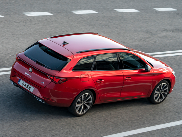 Roter SEAT Leon Sportstourer von hinten rechts auf Straße fahrend mit getönten Scheiben