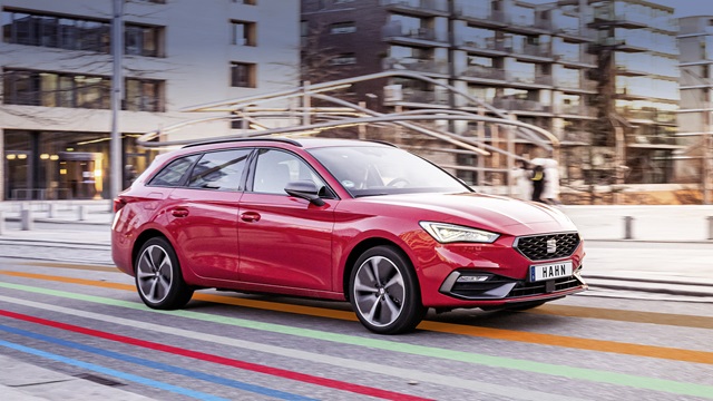 Roter SEAT Leon Sportstourer in Seitenansicht auf einer Straße mit farbigen Linien im urbanen Umfeld