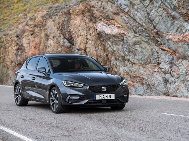 Grau-metallic SEAT Leon in Frontansicht auf einer kurvigen Bergstraße vor felsigem Hintergrund