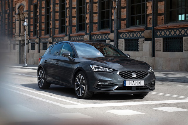 Grau-metallic SEAT Leon in Seitenansicht vor einem historischen Gebäude mit großen Fenstern und Zierfassade