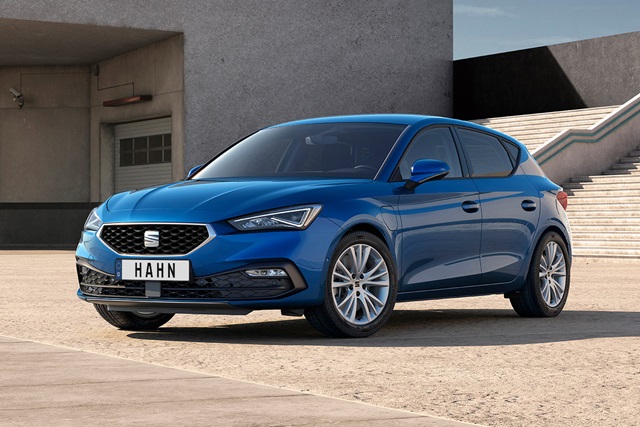 Blauer SEAT Leon Style E-Hybrid in Seitenansicht vor modernem Gebäude mit Treppe