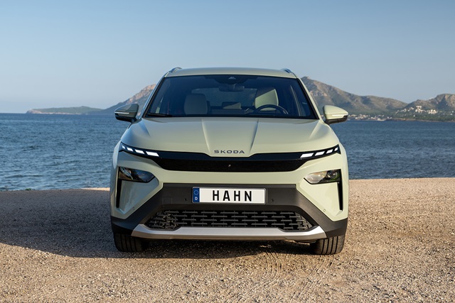 Frontansicht des grünen Skoda Elroq mit markantem Scheinwerferdesign und Kennzeichen 'HAHN' vor einer Küstenlandschaft