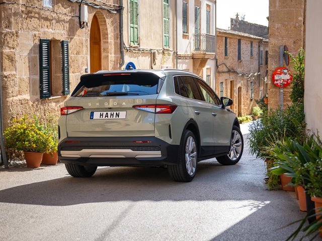 Heckansicht eines grünen Skoda Elroq in einer engen Gasse mit mediterranen Gebäuden und Pflanzen in Töpfen