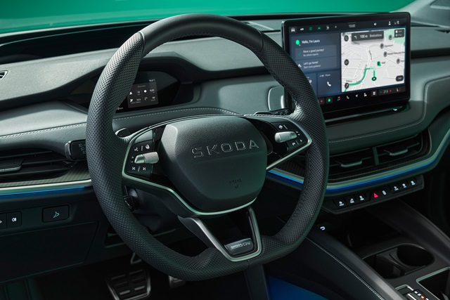 Lenkrad mit SKODA-Schriftzug und Multifunktionstasten vor digitalem Cockpit und großem Infotainment-Display im Innenraum des Skoda Elroq Sportline
