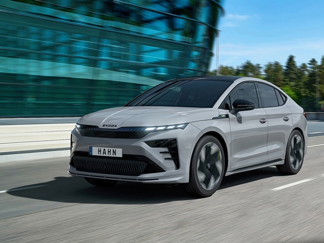 Grau lackierter Škoda Enyaq Coupé in Frontansicht auf Straße vor Glasfassade
