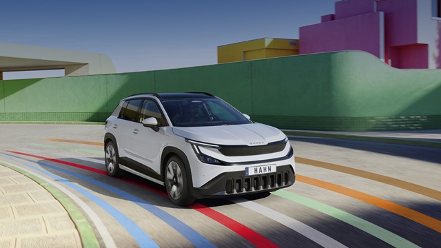 Weißer Skoda SUV in Frontansicht auf Straße mit bunten Linien vor grünem und pinkfarbenem Gebäude