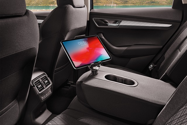 Tablet in Halterung an der Mittelarmlehne im Fond eines Škoda Karoq mit sichtbaren Lüftungsdüsen und Türverkleidung.