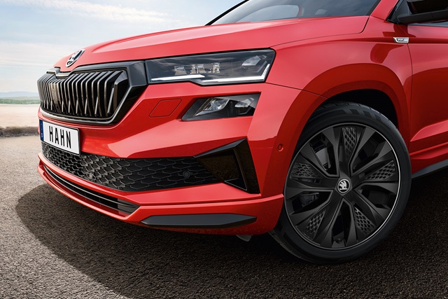 Nahaufnahme der Frontpartie eines roten Skoda Karoq mit schwarzem Kühlergrill, markanten Scheinwerfern, sportlicher Frontschürze und schwarzen Felgen.