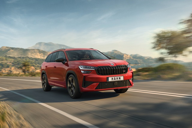 Roter Škoda Kodiaq RS fährt auf einer Landstraße mit Bergen im Hintergrund