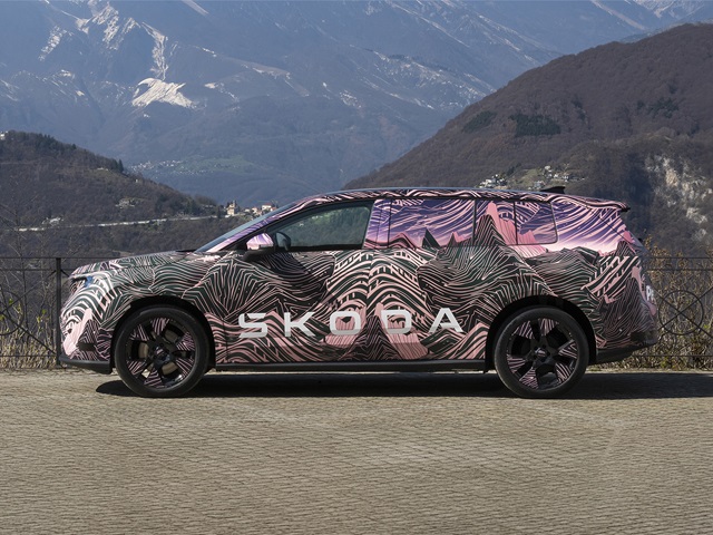 Seitenansicht eines Škoda Peaq Erlkönigs mit auffälliger Camouflage-Folie vor Bergkulisse