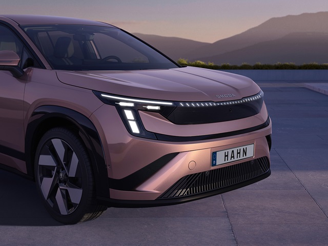 Vorderansicht des Škoda Peaq mit markanten LED-Scheinwerfern vor Bergkulisse bei Dämmerung.