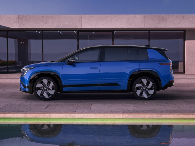 Seitliche Ansicht des blauen Škoda Peaq Sportline vor einem modernen Gebäude mit großen Fenstern und einem Wasserbecken im Vordergrund.