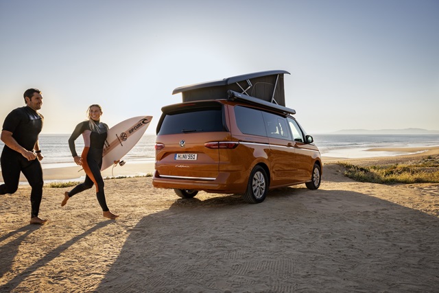 Der Volkswagen California Beach an der Küste mit zwei Surfern.