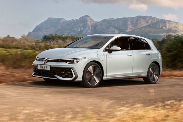 Weißer VW Golf GTE in Seitenansicht auf einer Landstraße vor Bergkulisse